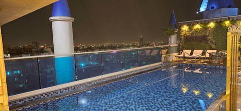       Rooftop infinity pool reflecting city lights with a distant urban skyline under the night sky.
  