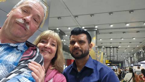       Casual selfie with two travelers and their driver inside a busy modern transport terminal.
  