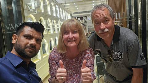       Guide and two travelers give thumbs up inside a stylish hotel lobby with mirrored walls.
  