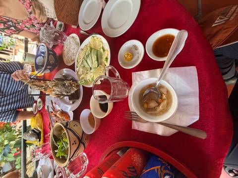       Shared Vietnamese meal table featuring fish, vegetables and dipping sauces.
  