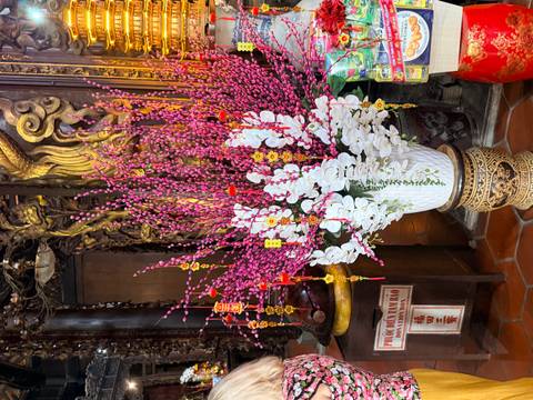       Decorative arrangement of pink and white blossoms inside an ornate Vietnamese temple.
  