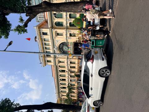      Crowds gather in front of the colonial-era Saigon Central Post Office on a sunny day.
  
