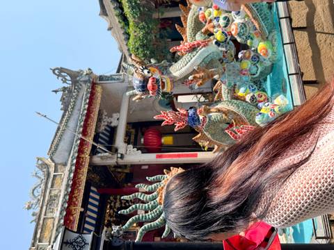       Colorful ceramic dragon statues in a temple courtyard partly blocked by a visitor’s hair.
  