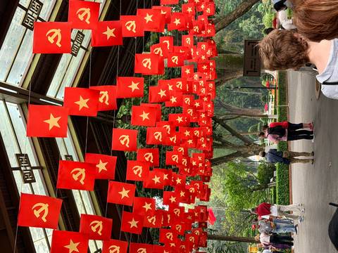       Ceiling decorated with rows of red communist and national flags at a Vietnamese historical site.
  