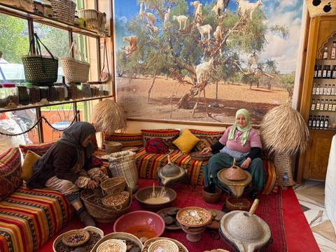       Women demonstrating traditional argan oil production inside a colorful Berber cooperative.
  