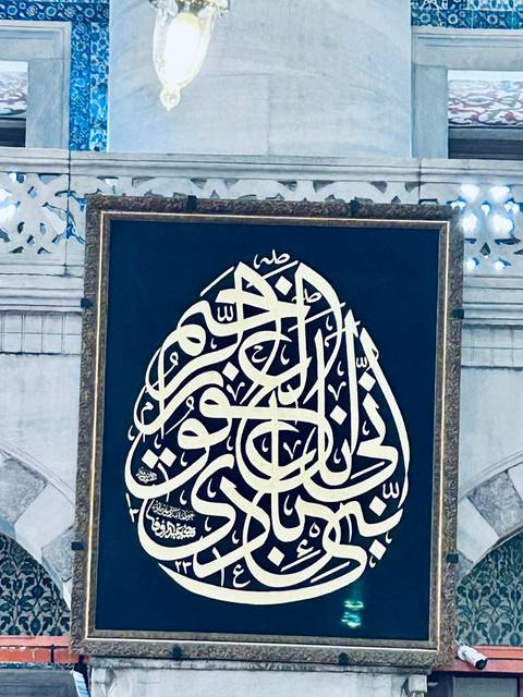      Framed panel of ornate Arabic calligraphy displayed inside an Istanbul mosque.
  