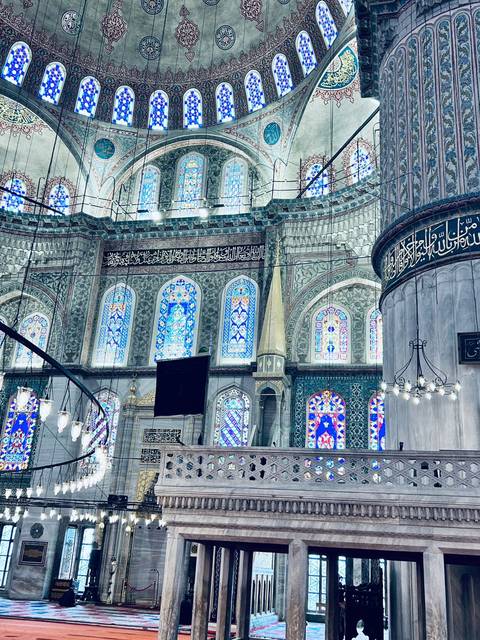       Detailed interior of a historic Istanbul mosque with turquoise tiles and stained glass windows.
  