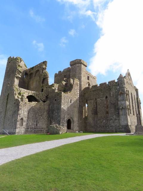       Ruins of the Rock of Cashel stand against a bright blue Irish sky.
  