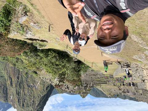       Travelers pose for a selfie with the terraces of Machu Picchu behind them.
  