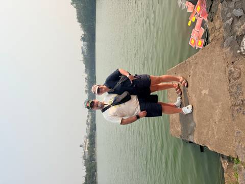       Couple standing on a concrete pier beside a calm urban lake on a hazy day
  