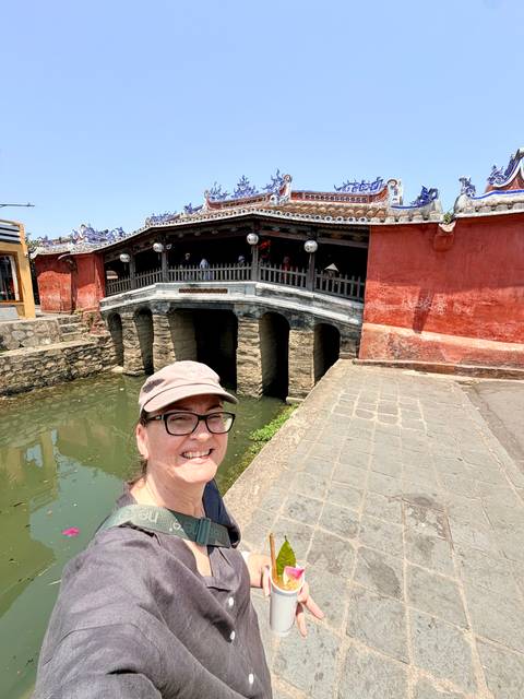       Selfie of a woman with the Japanese Covered Bridge and canal behind on a bright day
  