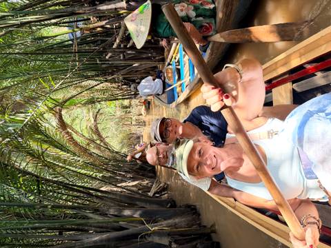       Tourists paddling narrow boats through lush nipa palm tunnels on muddy river
  