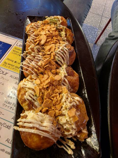       Close-up of freshly made takoyaki balls drizzled with mayo and topped with crispy garlic chips.
  