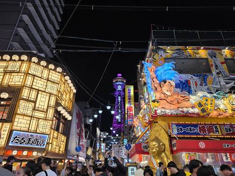       Neon-lit Shinsekai district with Tsutenkaku Tower glowing purple against the night sky in Osaka.
  
