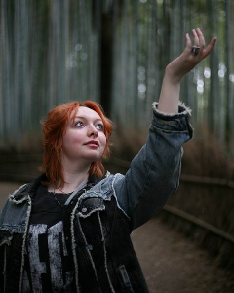       Woman reaching upward inside the serene bamboo groves of Arashiyama.
  
