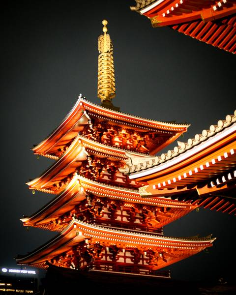       Illuminated multi-tiered pagoda with ornate eaves glowing against a dark night sky.
  