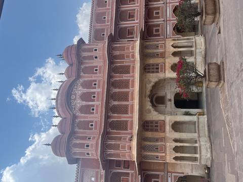       Elegant Mughal-style palace courtyard in Jaipur with arched windows and floral planter.
  