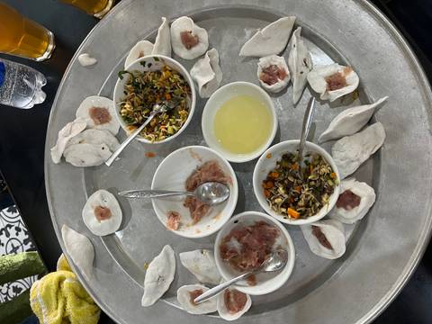       Large metal tray with partially assembled Vietnamese dumplings, bowls of fillings, and spoons from a cooking class.
  