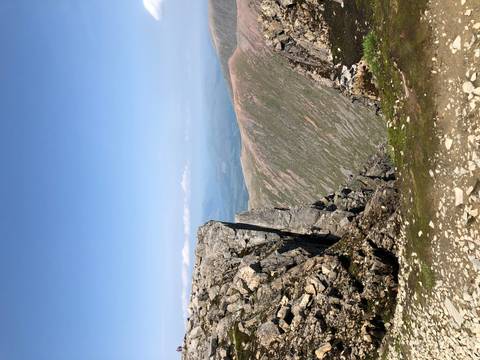       Rocky mountain ridge overlooking expansive valleys under a clear blue sky.
  