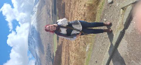       Smiling traveler with snow-dusted mountain backdrop and patchwork valley below.
  