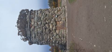       Large circular stone memorial cairn at historic battlefield site surrounded by moorland.
  