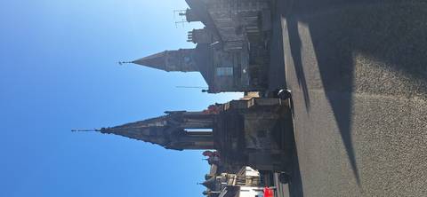       Stone market cross and clock tower casting long shadows down quiet village street.
  