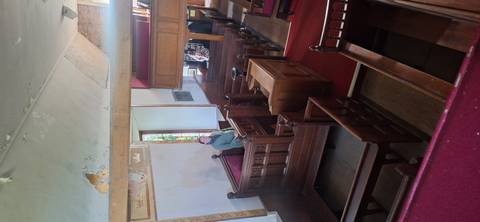       Interior of historic wooden church with visitor standing among polished pews and stained glass.
  
