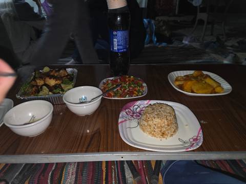      Night-time camp table with simple dishes and soda bottle lit by flash.
  