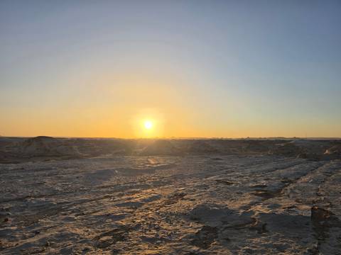       Sunset casts a warm glow over the rocky expanse of the White Desert.
  