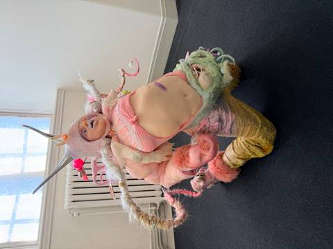       Person wearing an elaborate pastel fantasy costume posed inside a modern gallery space
  