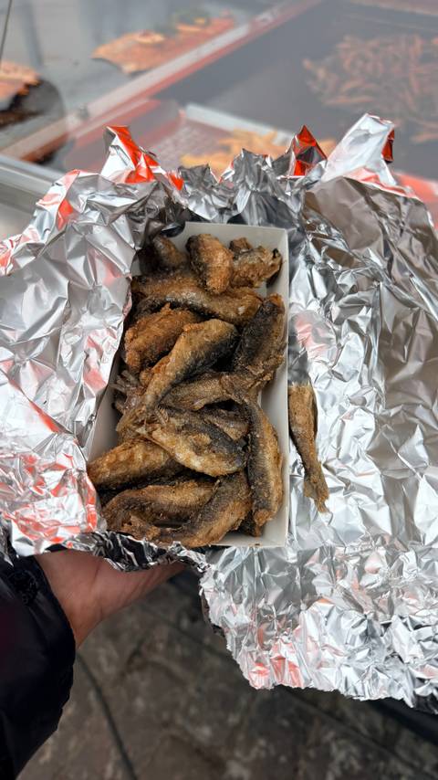       Box of small fried fish laid on foil ready for takeaway
  