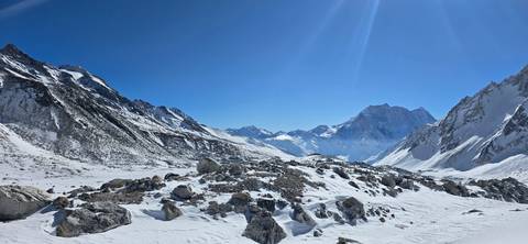       Wide snowy valley framed by rugged Himalayan mountains under a deep blue sky.
  