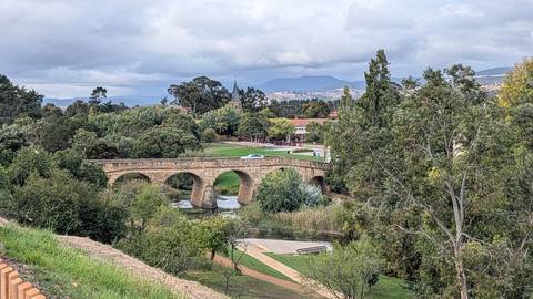       Historic sandstone Richmond Bridge spans a leafy river valley in Tasmania.
  