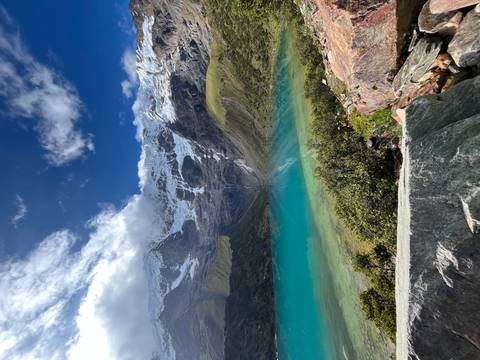       Brilliant turquoise Humantay Lake reflecting snow-capped peaks under dramatic sky.
  