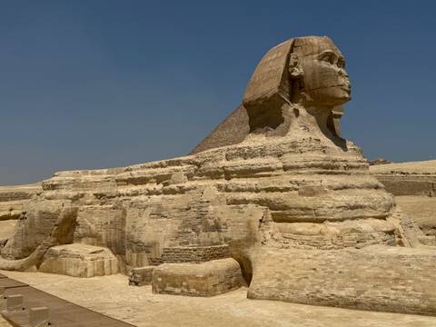       Side profile of the Great Sphinx of Giza set against a clear desert sky.
  