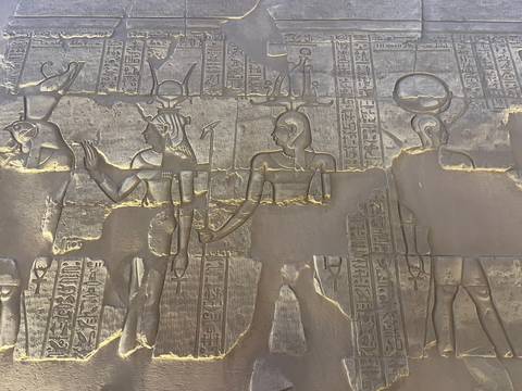       Close-up of ancient Egyptian wall carvings depicting gods and hieroglyphics.
  