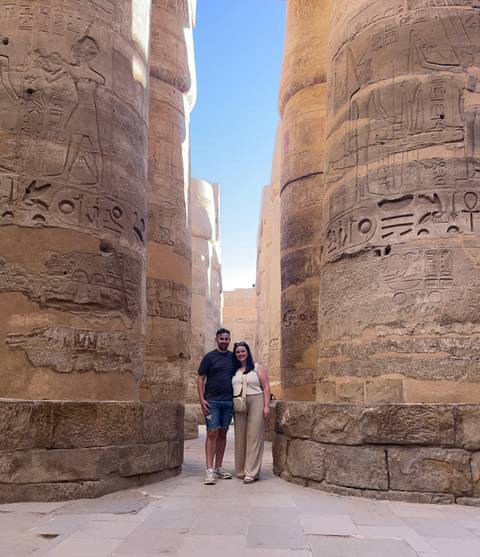       Couple surrounded by giant hieroglyph-covered columns inside Karnak Temple.
  
