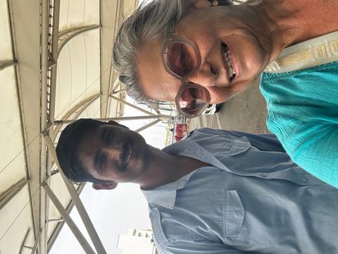       Selfie of smiling older traveler with a young driver outside an airport terminal in India.
  