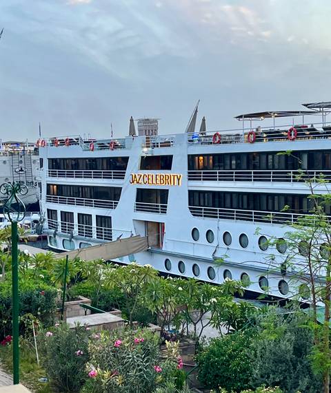       Side view of Jaz Celebrity Nile cruise vessel docked with circular windows and nameplate
  