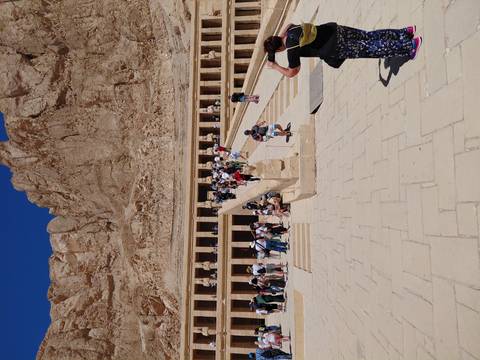       Grand temple of Hatshepsut at Deir el-Bahri with long ramp and crowds of visitors against steep cliffs
  