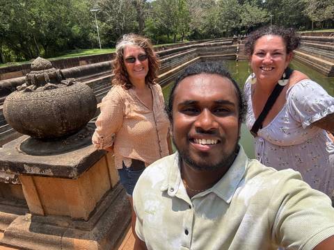       Travellers taking a selfie in front of an ancient stone bath at a historic Sri Lankan site
  