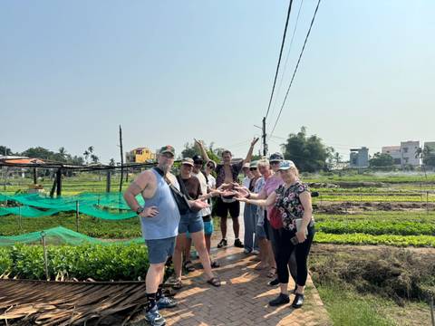       Travellers standing on narrow garden paths of a Vietnamese organic farm, gesturing playfully
  