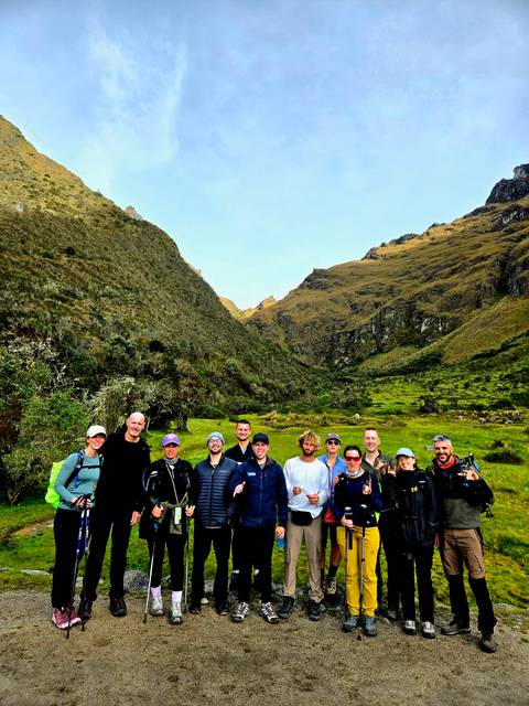       Hikers posed in a green Andean valley surrounded by steep hillsides
  