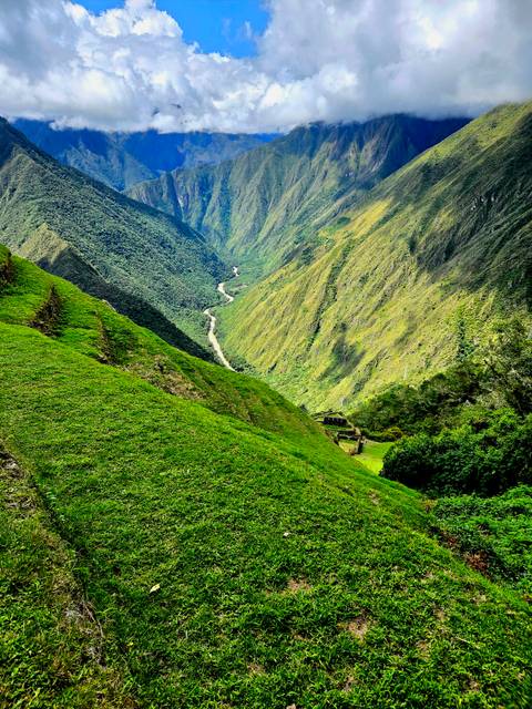       Steep emerald slopes descending to a winding river deep in the Andean valley
  