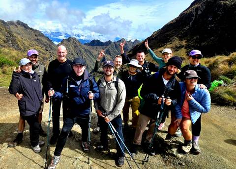       Happy hikers cheering at a high mountain pass with distant peaks behind
  
