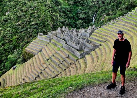       Traveler standing beside terraced Inca ruins cascading down a lush hillside
  