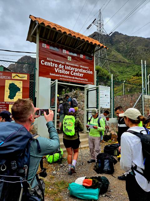       Visitors queue at the Inca Trail visitor center entrance while taking photos
  