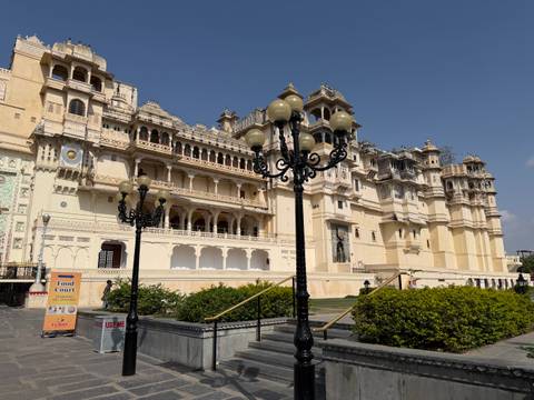       Historic palace facade with ornate balconies framed by decorative lampposts under a cloudless sky
  