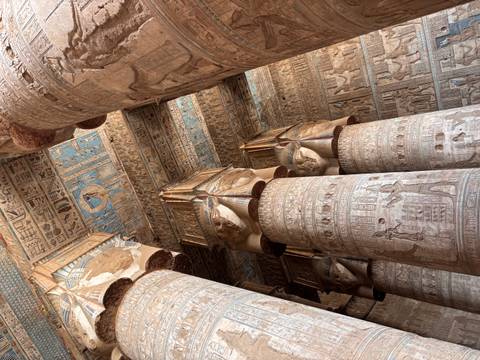       Interior view of temple hypostyle hall with towering carved columns and blue painted ceilings
  