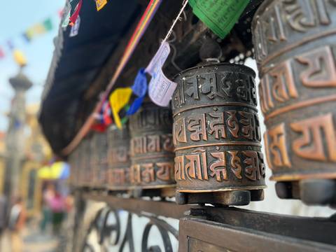       Close-up of bronze Tibetan prayer wheels with decorative script at a Buddhist site.
  